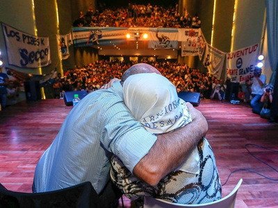 Hebe de Bonafini y el presidente del Frente Grande Mario Secco de espaldas abrazandose en un acto dentro de un teatro